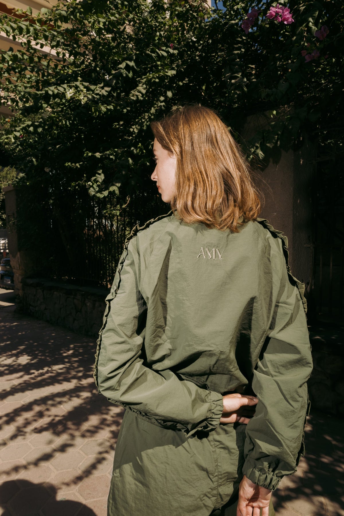 Olive jacket from the back with the AMLY logo