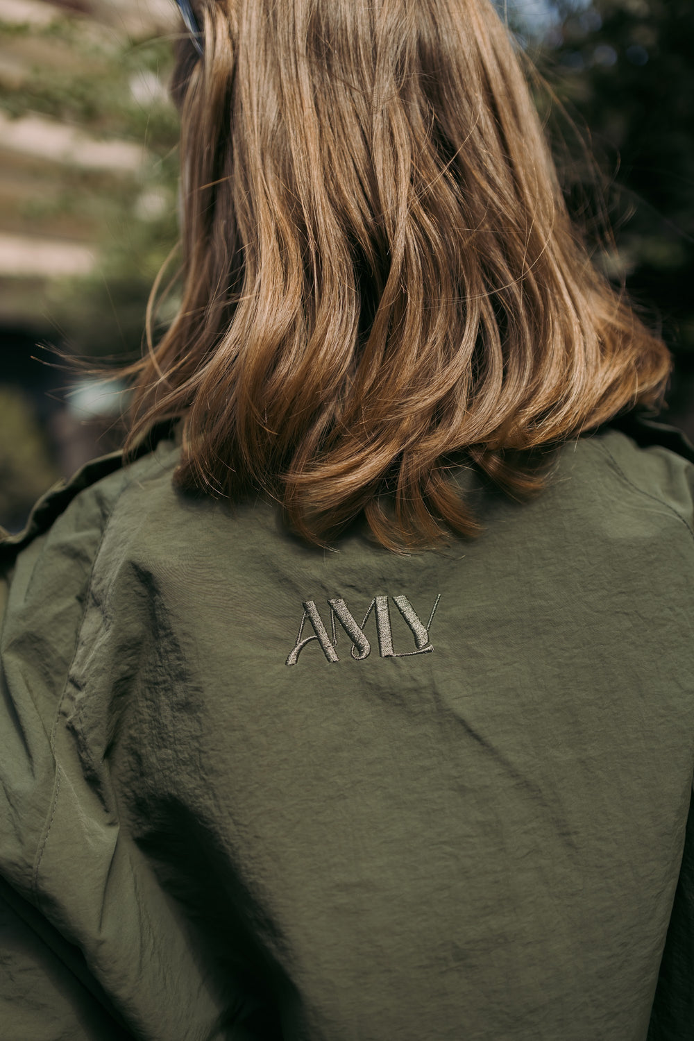 Close-up of the AMLY logo on the olive jacket
